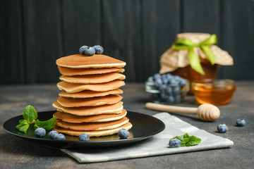 Delicious pancakes, with fresh blueberries, strawberries and caramel on a dark background.