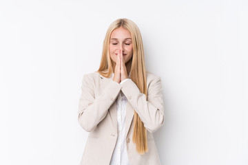 Young business blonde woman on white background holding hands in pray near mouth, feels confident.