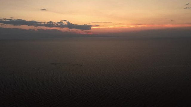 Descending shot of a scenic sunset at the Mediterranean sea, Greece. Drone, aerial video. Pedestal shot, camera descending. Fish farm visible at the distance.