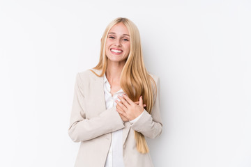 Young business blonde woman on white background laughing keeping hands on heart, concept of happiness.