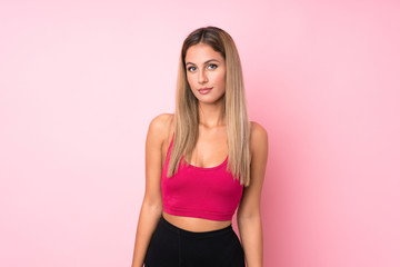 Young sport blonde woman over isolated pink background stretching arm