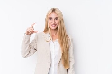 Young business blonde woman on white background holding something little with forefingers, smiling and confident.