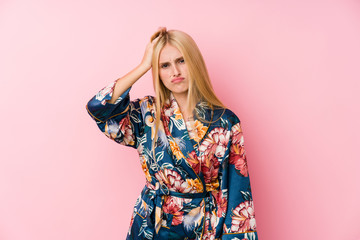 Young blonde woman wearing a kimono pajama being shocked, she has remembered important meeting.