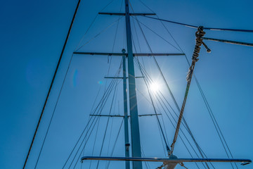 Mast of the yacht against the blue sky with sun glare. Summer recreation concept. High detailed photo