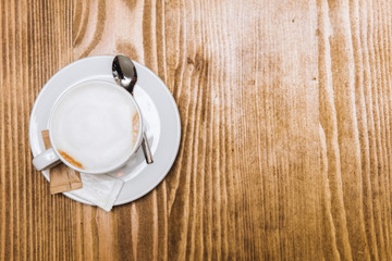 Cup of cappuccino coffee and croissants on a wooden table