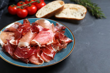 Tasty fresh prosciutto slices on black table