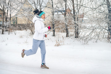 Fototapeta na wymiar Running sport woman. Female runner jogging in cold winter forest wearing warm sporty running clothing and gloves