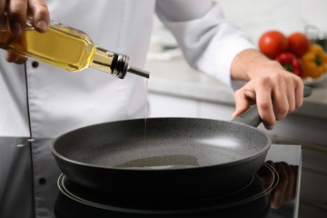 Man pouring cooking oil from bottle into frying pan, closeup