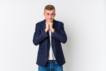 Young business caucasian man keeps hands under chin, is looking happily aside.