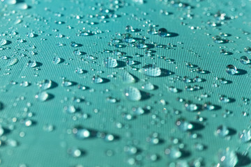 Close-up of natural and refreshing raindrops on the fabric of a colored umbrella.