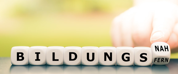 Hand dreht einen Würfel und ändert den Ausdruck bildungsfern in bildungsnah.