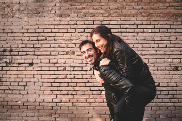 Fototapeta na wymiar Couple in piggyback having a good time of laughter and love to celebrate their upcoming wedding.