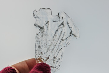A piece of transparent ice in the hands. Spring time.