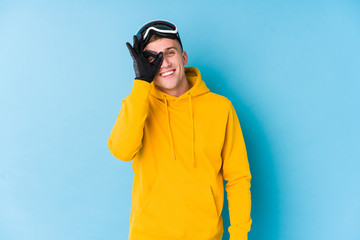 Young skier man excited keeping ok gesture on eye.