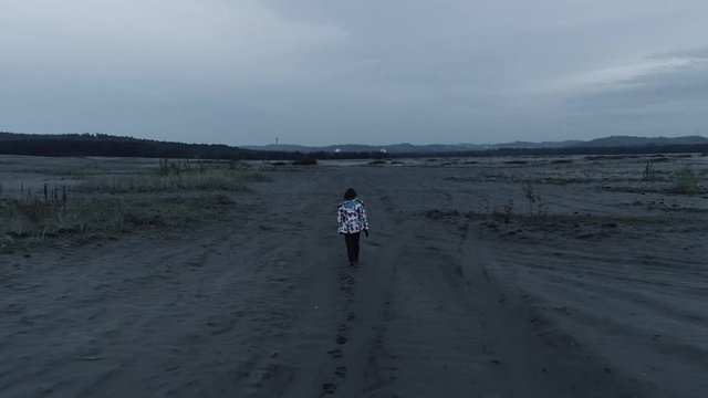 Child walking through an empty, desolated land. Aerial, drone video. Slow motion. Poland, Bledow desert.