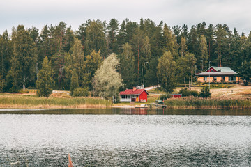 Fototapeta premium wooden building on the lake shore near autumn pine forrest