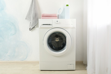 Modern washing machine against blue wall, space for text