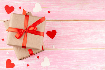 Valentine's Background with Two Gift Boxes with Red Ribbon Bow and Confetti Paper Hearts on Pink Wooden Background. Love, Romance, Happy Valentines Day Concept. Top View, Copy Space