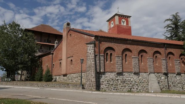 Zica monastery in Serbia with red facades and protecting walls 4K panning video