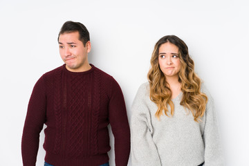 Young couple posing in a white background confused, feels doubtful and unsure.