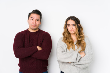 Young couple posing in a white background unhappy looking in camera with sarcastic expression.