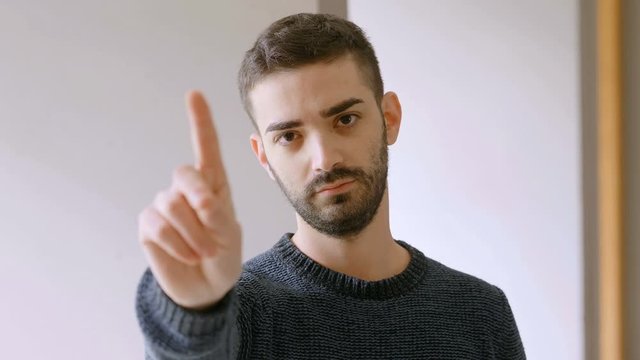 young bearded man looking at camera and saying no with finger