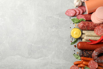 Different sausages and spices on grey background, space for text