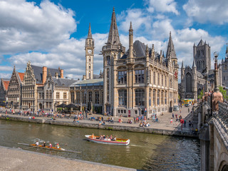 People in the Graslei, quay in the promenade next to river Lys in Ghent, Belgium and St Michael's...