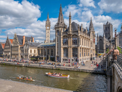 People in the Graslei, quay in the promenade next to river Lys in Ghent, Belgium and St Michael's Bridge on a sunny day. Beautiful architecture  of the medieval city. in Ghent, Belgium.