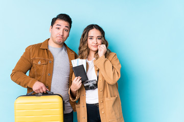 Young couple ready for a travel isolated with fingers on lips keeping a secret.