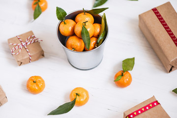 Christmas decoration of mandarin in an iron small bucket, Christmas tree, gifts  on the white wooden boards background