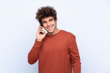 Young caucasian man over isolated blue background keeping a conversation with the mobile phone