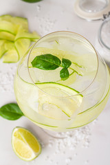 water with ice and cucumber in a glass on a white background close-up
