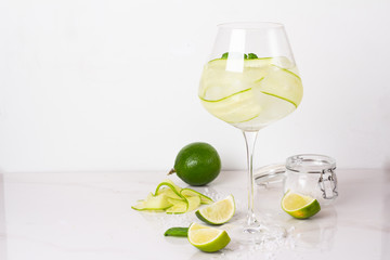 water with ice and cucumber in a glass on a white background
