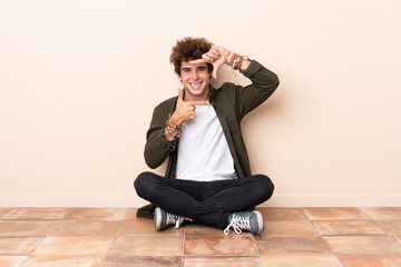 Young caucasian man sitting on the floor focusing face. Framing symbol