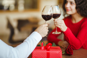 Young couple having a romantic dinner and toasting with glass of red wine. Sweet couple celebrate their anniversary. Valentines day celebration concept. Relationship, surprise and love concept.