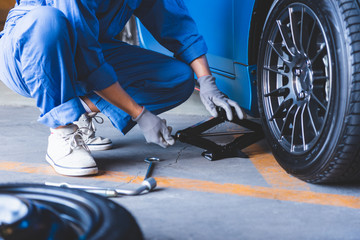 Car mechanics changing tire at auto repair shop garage. Transportation and Business working people...