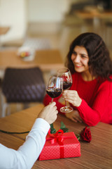 Young couple having a romantic dinner and toasting with glass of red wine. Sweet couple celebrate their anniversary. Valentines day celebration concept. Relationship, surprise and love concept.