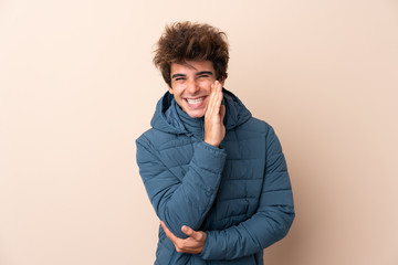 Man wearing winter jacket over isolated background whispering something