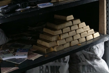 Money bags, currency and the stack of gold blocks on the strongbox shelves. A close-up view inside of the hacked safe after the bank robbery.