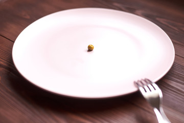 One pea on a plate. The concept of diet, anorexia, poverty.