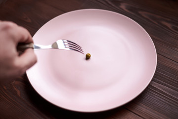 One pea on a plate. The concept of diet, anorexia, poverty.