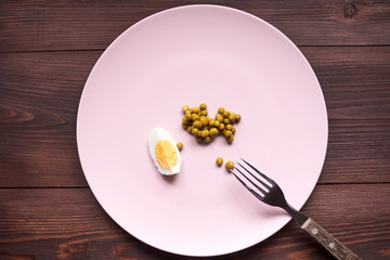 Peas and chicken egg on a plate. Poor, poor food. The concept of diet, malnutrition.
