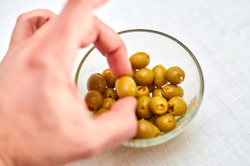 A male hand takes an olive from a cup.
