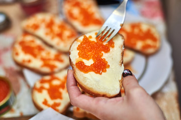 Woman makes sandwiches with red caviar. Bread and butter and salmon caviar on top.