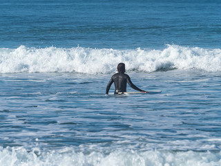 Man with a surfboard entering the sea, in Sopelana, Basque country.