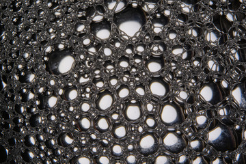 Abstract black background with soap bubbles in the water. Foam in high magnification. Close-up. Macro.