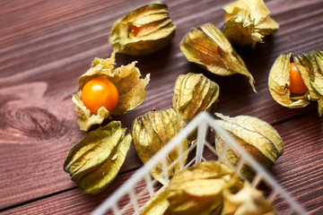 Edible physalis berries on a dark brown wooden background.
