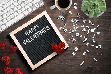 HAPPY VALENTINES DAY message on a letter board surrounded by letters, a coffee and a keyboard on wooden background
