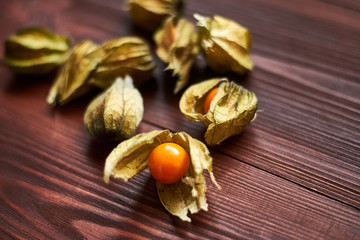 Edible physalis berries on a dark brown wooden background.